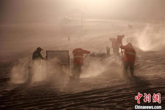 圖為敦煌市鳴沙山月牙泉景區(qū)“駱駝保姆”清理駱駝糞便?！垥粤?攝