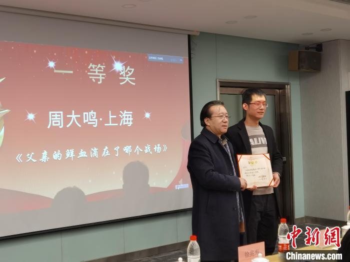 圖為作家、西北師范大學(xué)新聞與傳媒學(xué)院院長(zhǎng)徐兆壽頒發(fā)一等獎(jiǎng)證書(shū)，代領(lǐng)獎(jiǎng)?wù)呱吓_(tái)領(lǐng)獎(jiǎng)?！钅?攝