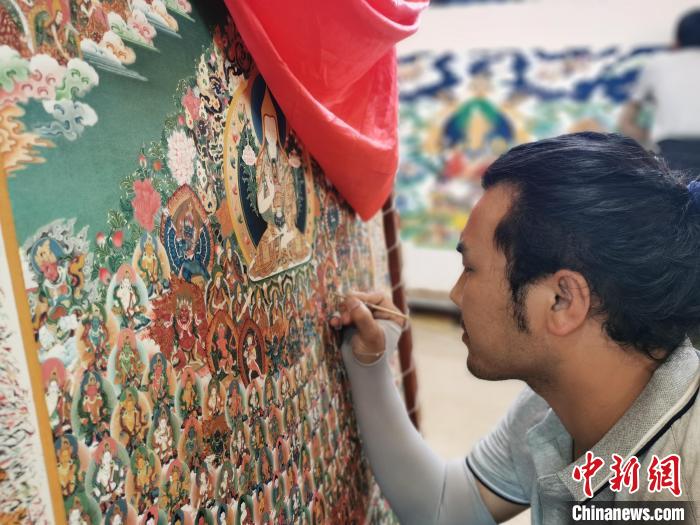 圖為更登才讓的徒弟繪畫唐卡?！?zhí)砀?攝