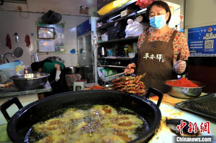 圖為平安驛·河湟民俗文化體驗地內(nèi)的商戶炸干板魚?！⊙Φ?攝