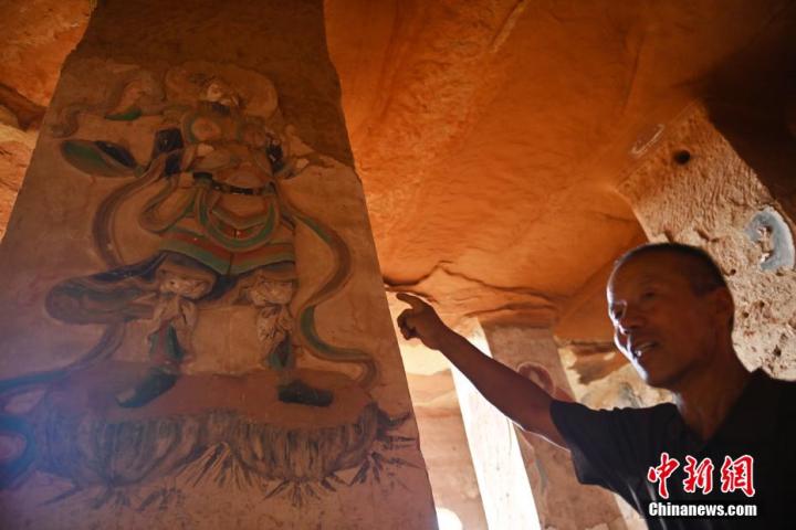 7月15日，甘肅省平?jīng)鍪袥艽h百里石窟長廊羅漢洞石窟內(nèi)，該窟文保員郭建平介紹窟內(nèi)石刻彩繪壁畫。郭建平家中三代人曾自發(fā)保護(hù)羅漢洞石窟。羅漢洞石窟遺存40余個窟龕，以北魏至清代風(fēng)格為主。中新社記者 李亞龍 攝</p>
<p>